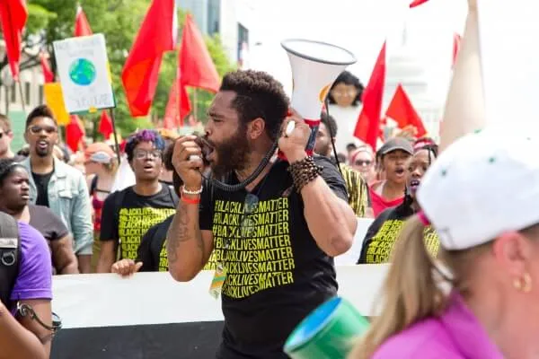 A man speaking through a megaphone at a street march.