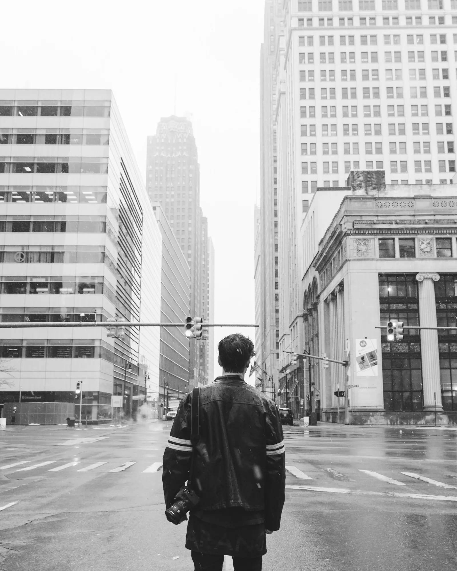 A person standing in a city street among tall office buildings.