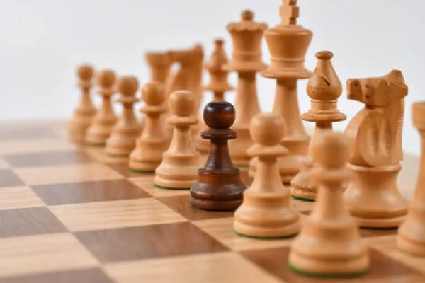 Wooden chess pieces lined up on a chessboard.